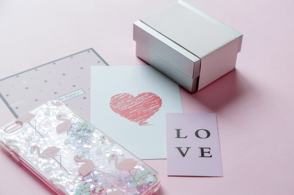 Gift box, phone case and greeting cards on pink background