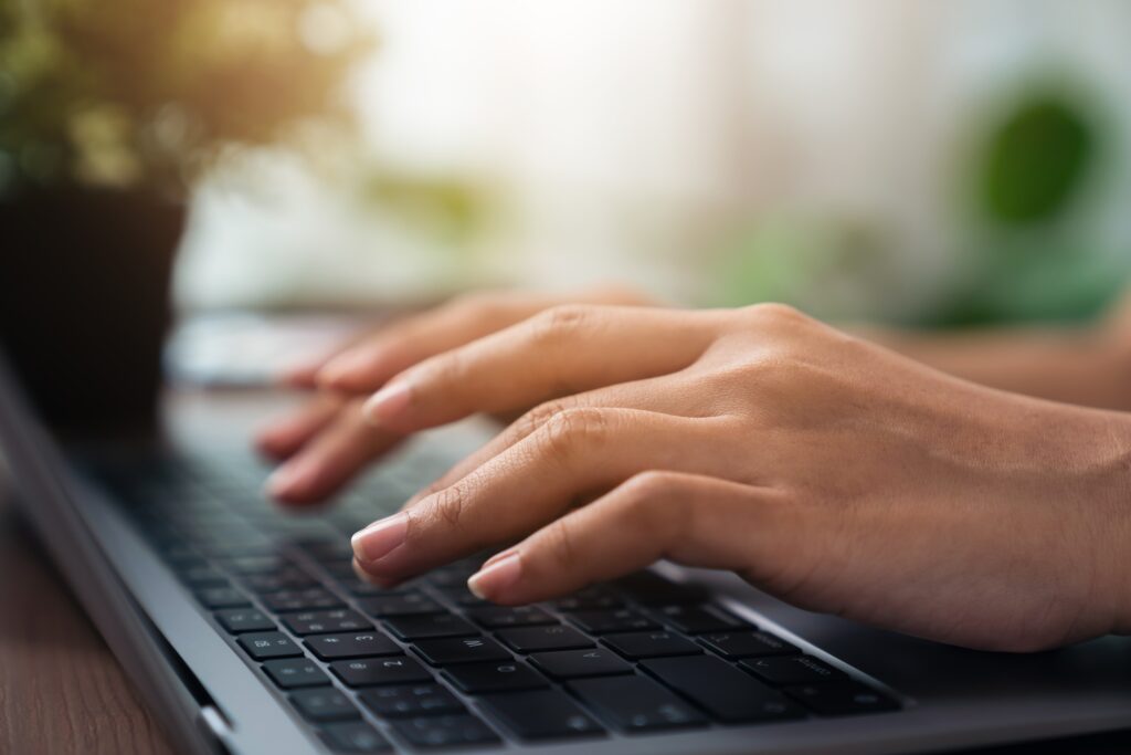 Woman using laptop and hand typing on the computer keyboard in the office.